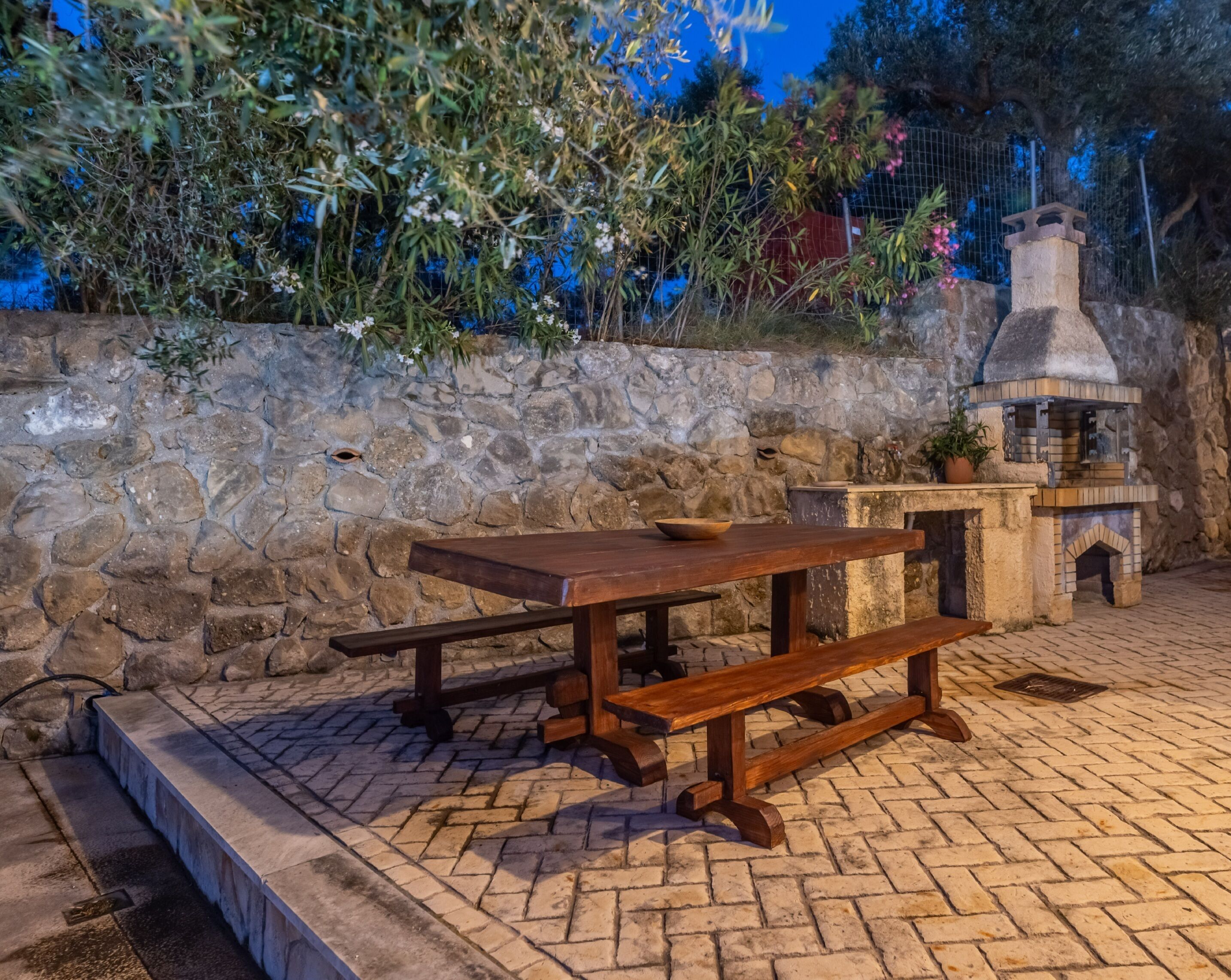 A stone wall with a rustic outdoor seating area featuring a wooden table and benches.