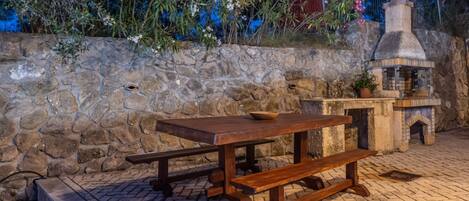 A stone wall with a rustic outdoor seating area featuring a wooden table and benches.