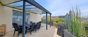 A covered patio with a table and chairs, a wooden cabinet, and a view of the surrounding landscape. - Le Refuge Une Parenthèse en Pleine Nature (Neuillé-Pont-Pierre)