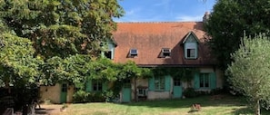 Ein zweistöckiges Haus mit roten Ziegeln, grünen Fensterläden und einer kleinen Veranda.