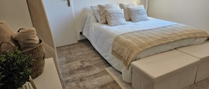 Ein Schlafzimmer mit einem Bett, Kissen, einem Nachttisch und einer Pflanze.