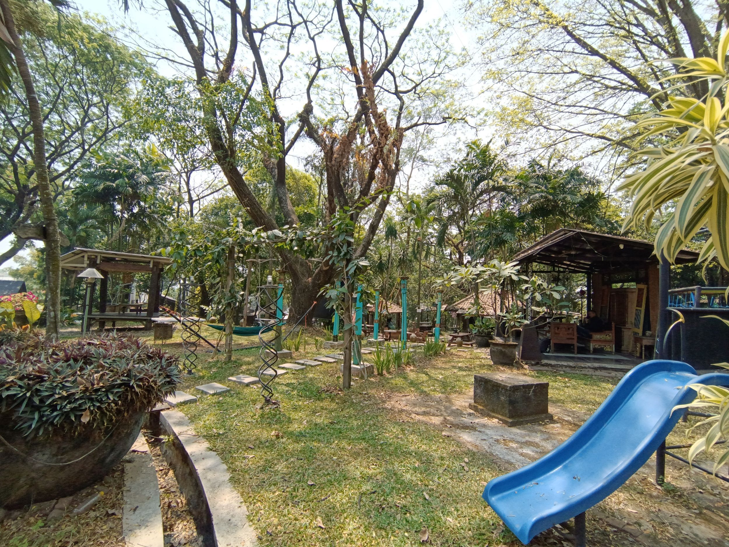 A playground with a blue slide, swings, and a small shelter.
