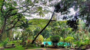 A pool surrounded by lush greenery and trees. - Grand Mulia Sakinah Boutique Resort (Pandaan)