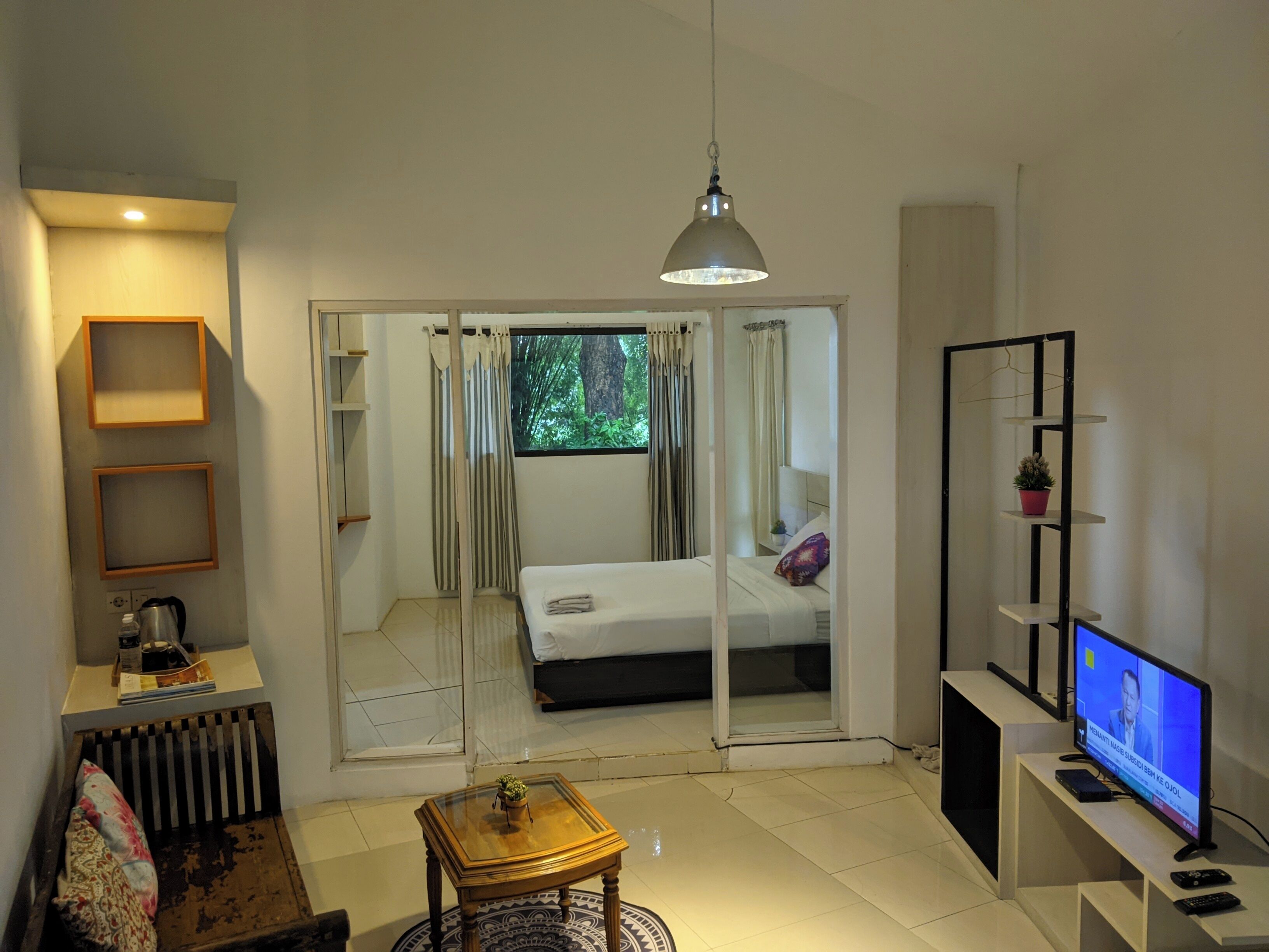A modern bedroom with a bed, a TV, and a sliding door leading to a balcony.