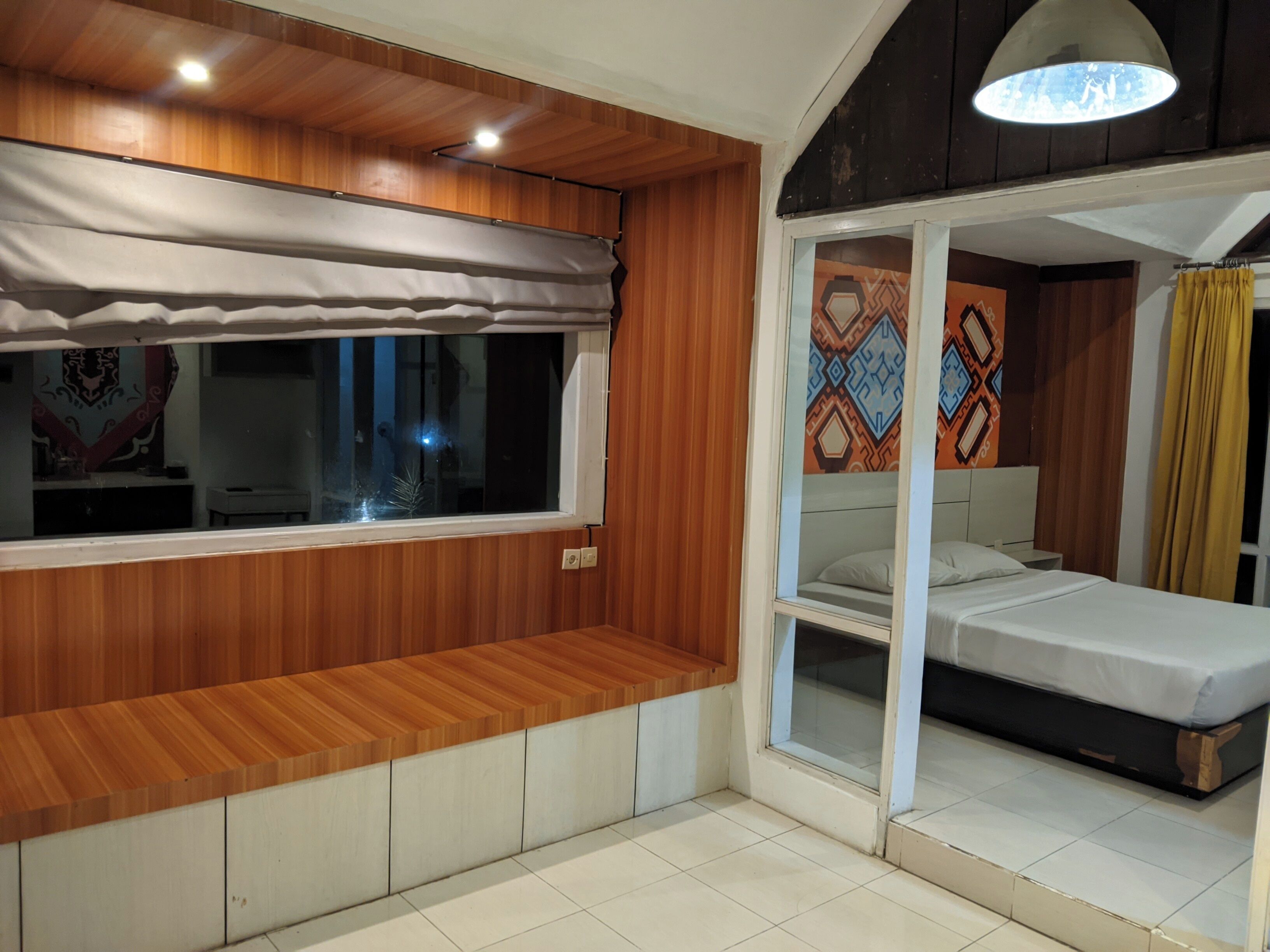 Un dormitorio con un banco de madera, una cama y un ventanal con cortinas.
