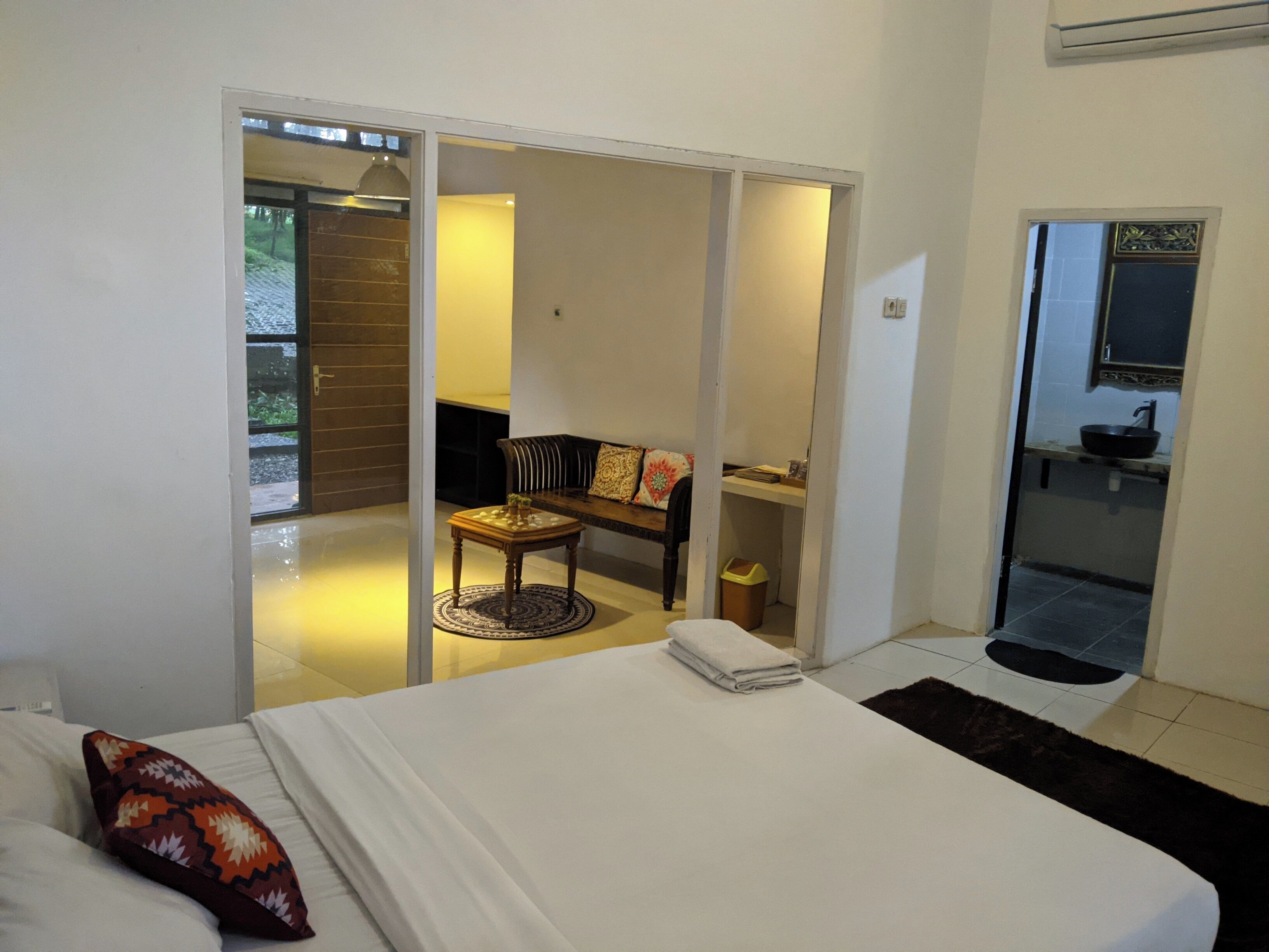 Ein Schlafzimmer mit Bett, einem Sessel, einem kleinen Tisch und Blick auf einen Balkon.