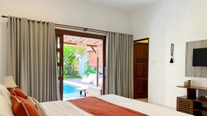 Ein Hotelzimmer mit Bett, Fernseher, Schreibtisch und Blick auf einen Außenpool.