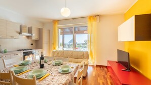 A modern kitchen with a dining area, a sofa, and a TV on a red stand. - Il Rifugio by Interhome (Città Sant'Angelo)