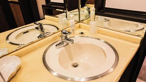 Et badeværelse med to håndvaske, et spejl og toiletartikler.