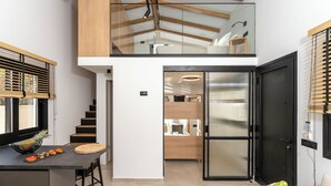 A modern kitchen with a dining area, a staircase, and a living space with a sofa and a table. - GEMM Beach House - Beachfront Apartment in Hersonissos (Hersonissos)