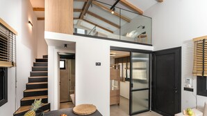 A modern interior with a staircase, a dining area with fruits, and a glass door leading to another room. - GEMM Beach House - Beachfront Apartment in Hersonissos (Hersonissos)