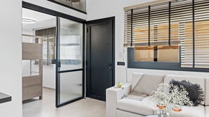 A modern interior with a sliding door, a sofa with decorative pillows, and a window with blinds. - GEMM Beach House - Beachfront Apartment in Hersonissos (Hersonissos)