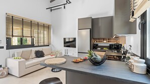 A modern kitchen with a built-in oven, a coffee machine, and a wine bottle on the counter. - GEMM Beach House - Beachfront Apartment in Hersonissos (Hersonissos)