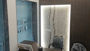 A reception desk with a marble-like design, a modern chandelier, and a wall with vertical lines. - Hotel Sunrise Ecostay  (New Delhi)