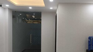 A room with a ceiling fan, recessed lighting, a patterned floor, and a glass door leading to a bathroom. - Hotel Sunrise Ecostay  (New Delhi)