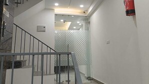 A modern interior with a staircase, a fire extinguisher, and a patterned glass door. - Hotel Sunrise Ecostay  (New Delhi)