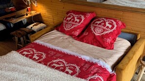 A cozy room with a wooden bed, a small desk with a laptop, and a chair.