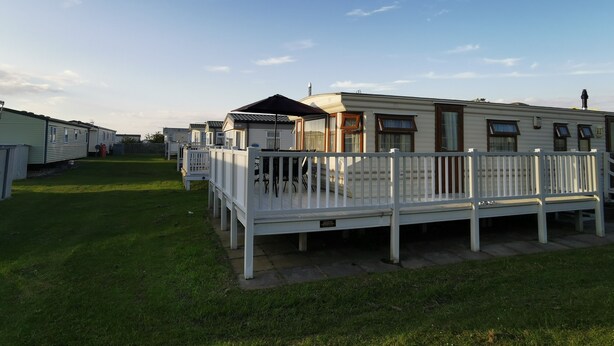 Une rangée de maisons mobiles dotées de balustrades blanches et bordée d’une pelouse verdoyante.