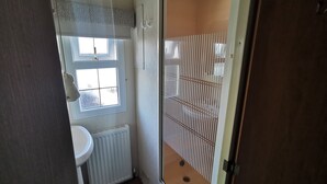 Une petite salle de bain avec des toilettes, un lavabo et une fenêtre.