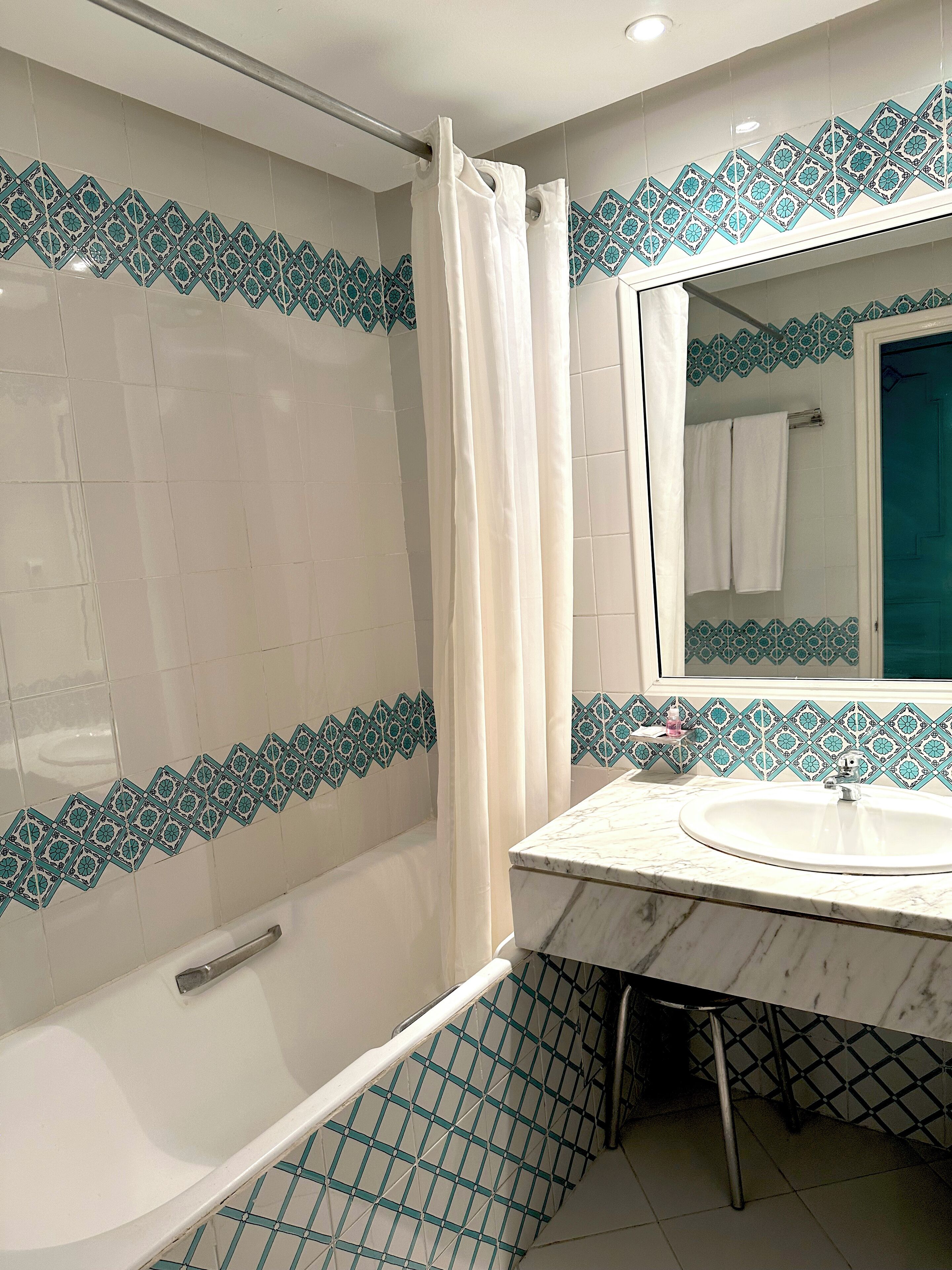 Een badkamer met een douche, een wastafel en een spiegel.
