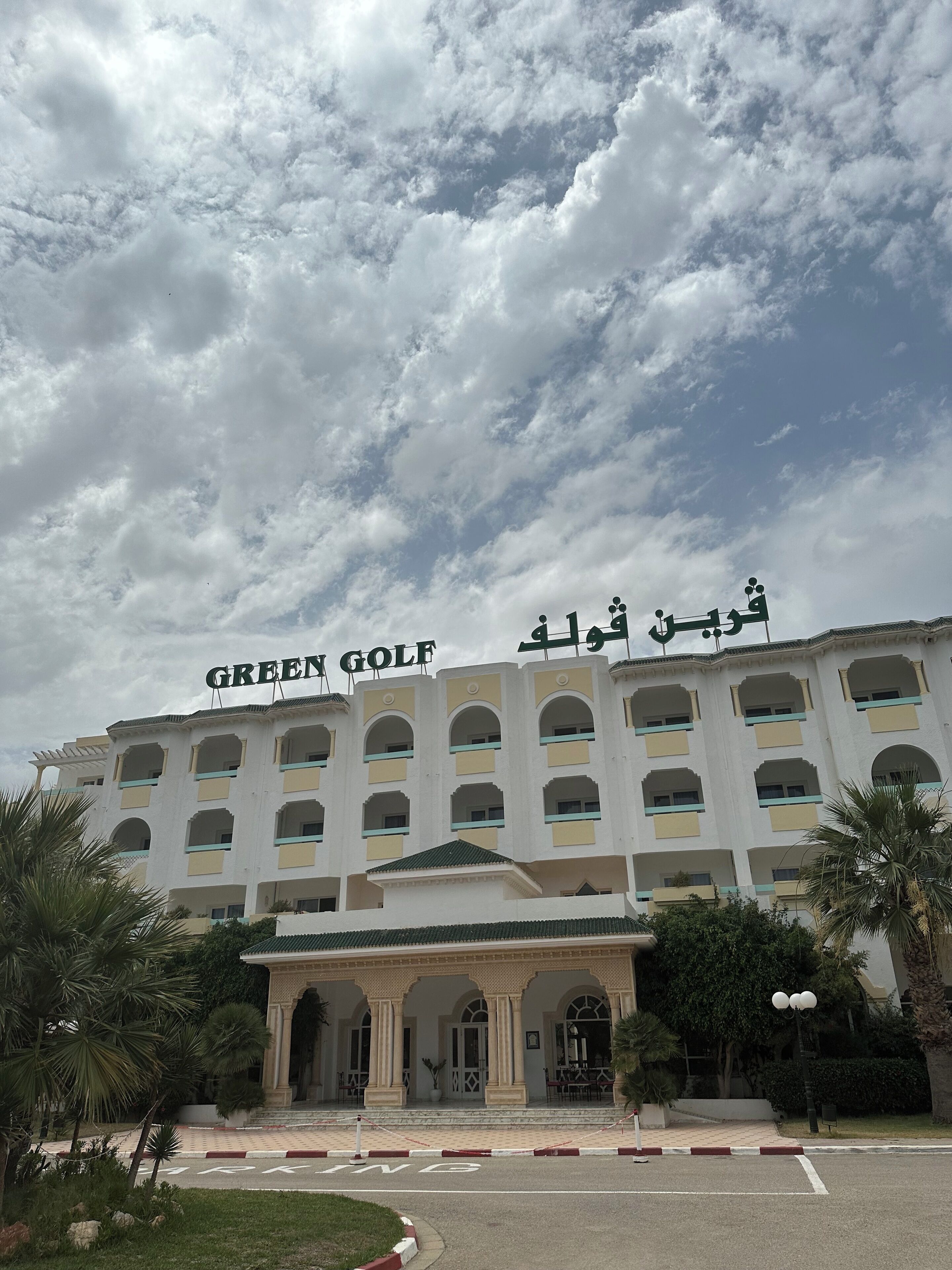 Un hotel llamado "Green Golf" de estilo arquitectónico tradicional, con varios balcones y una entrada central con galería cubierta.