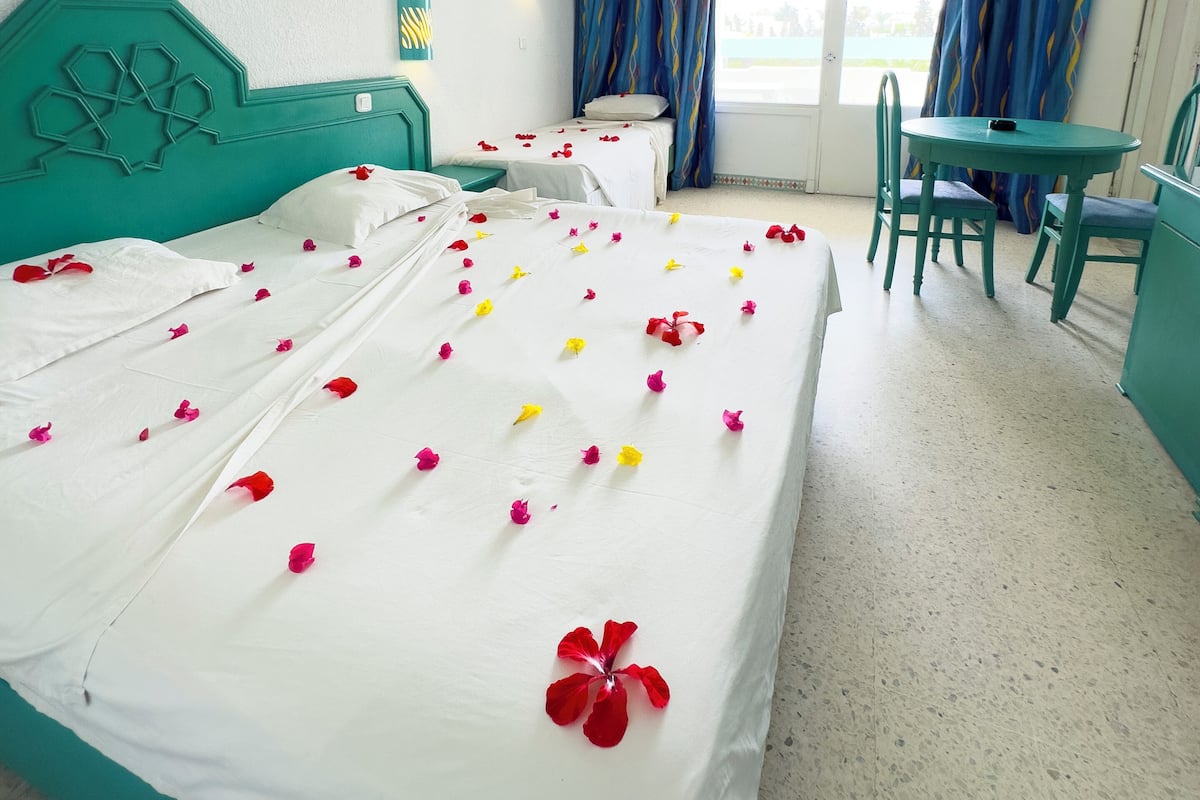 A hotel room with two beds, a desk, and a chair.