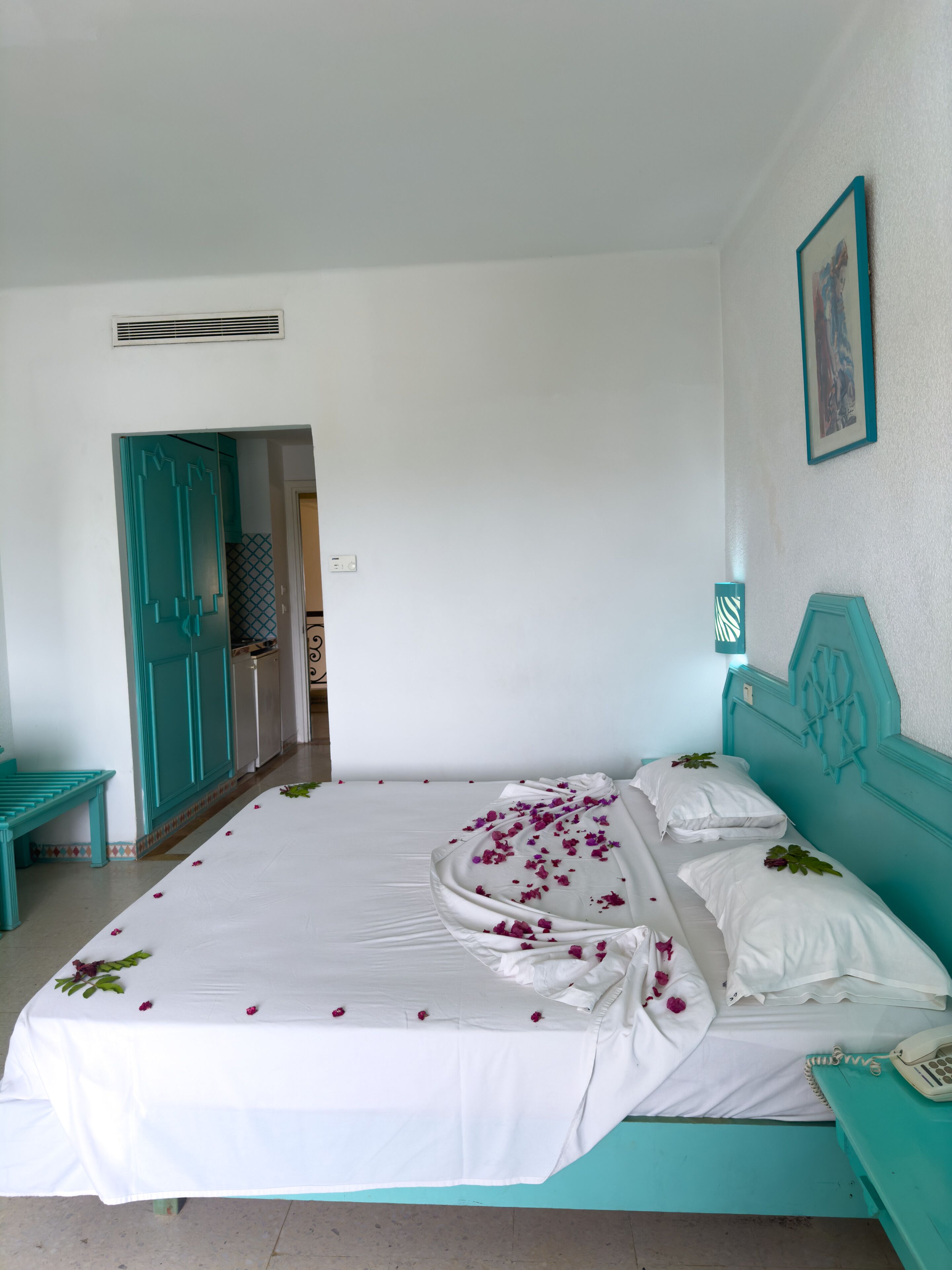 A bedroom with a bed, a bench, and a door.