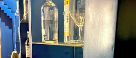 A bar area with various bottles and a wine glass on shelves.