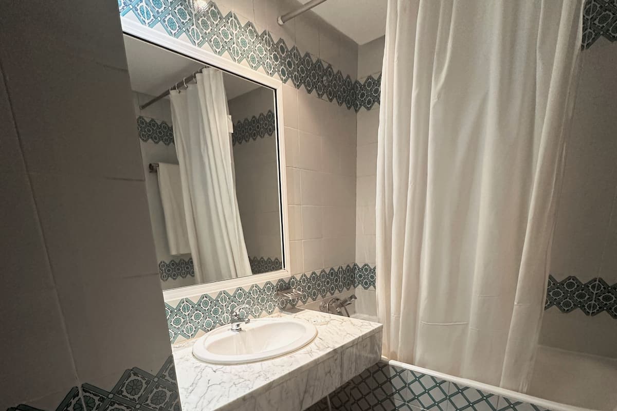 A bathroom with a white sink, a mirror, and a shower curtain.