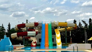 A swimming pool with a water slide structure in the background. - Green Golf Hammamet (Hammamet)