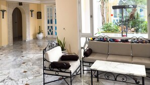 A spacious lobby with a marble floor, a sofa, a bench, and a large arched window offering a view of the outdoors. - Green Golf Hammamet (Hammamet)