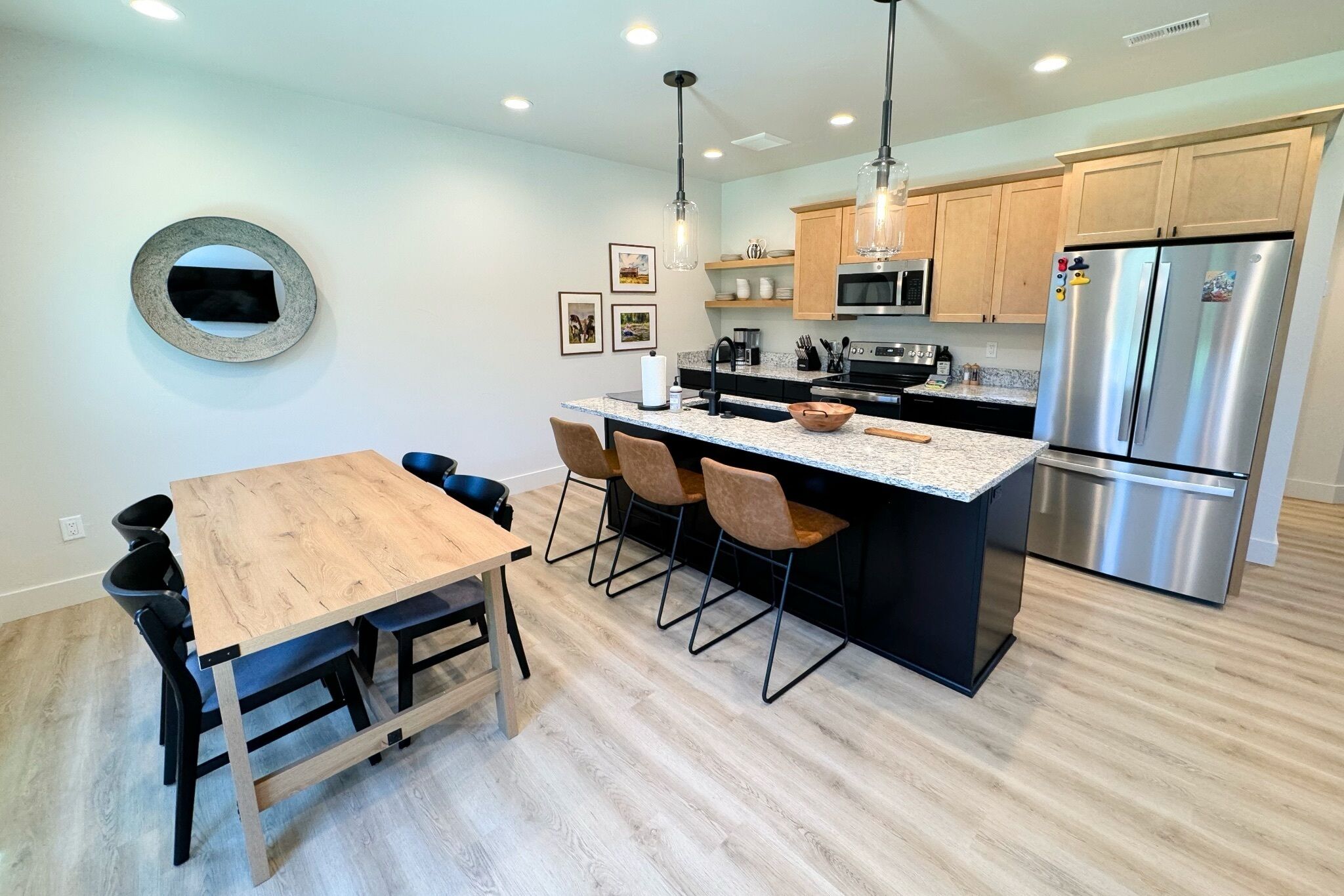 Een moderne keuken met een centraal eiland, een houten eettafel en barstoelen.