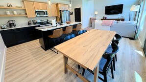 Una cocina moderna con una isla central, armarios negros y una mesa de madera con cuatro sillas.
