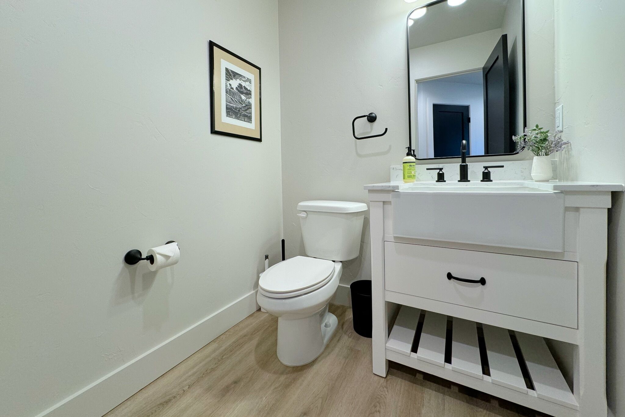 A modern bathroom with a toilet, sink, and mirror.