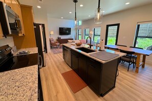 Una cocina moderna con encimeras de granito, una isla central y un comedor con mesa y sillas.