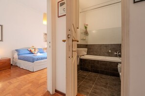 A bedroom with a bed, a bedside table, and a wooden floor. - Casa Lucrezio Prati Saint Peter's Church (Roma)