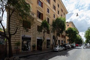 A street with a row of buildings, some with storefronts, and parked cars. - Casa Lucrezio Prati Saint Peter's Church (Roma)