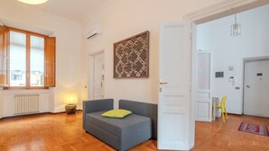 Ein Zimmer mit grauem Sofa, Holzboden, Wandpaneel und weißer Tür.