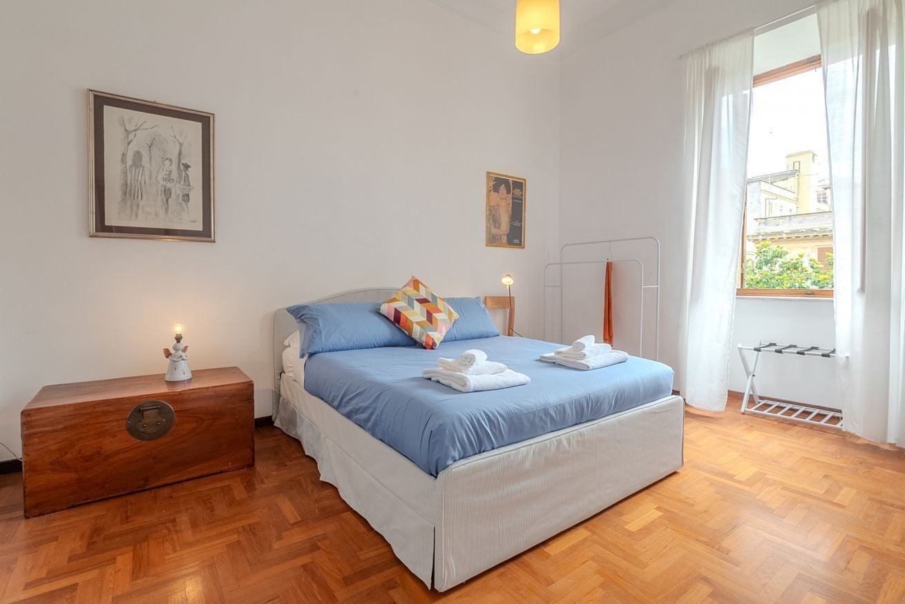 A bedroom with a bed, nightstand, dresser, and a window with curtains.