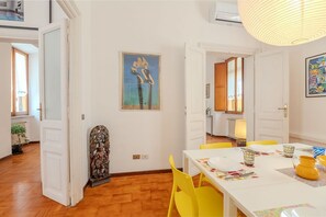 An open door leading to a dining area with a table set for four, a hanging light fixture, and a wall-mounted painting. - Casa Lucrezio Prati Saint Peter's Church (Roma)