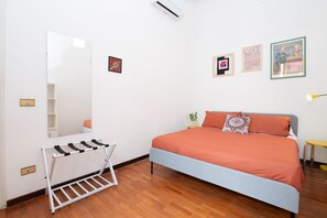 Une chambre à coucher avec un lit, un miroir, un étendoir et un mur orné de tableaux.