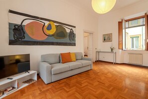 Un salon avec un canapé, un téléviseur, des œuvres d’art et un plancher en bois.