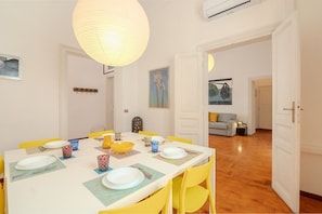 A dining area with a white table, yellow chairs, and a hanging light fixture. - Casa Lucrezio Prati Saint Peter's Church (Roma)
