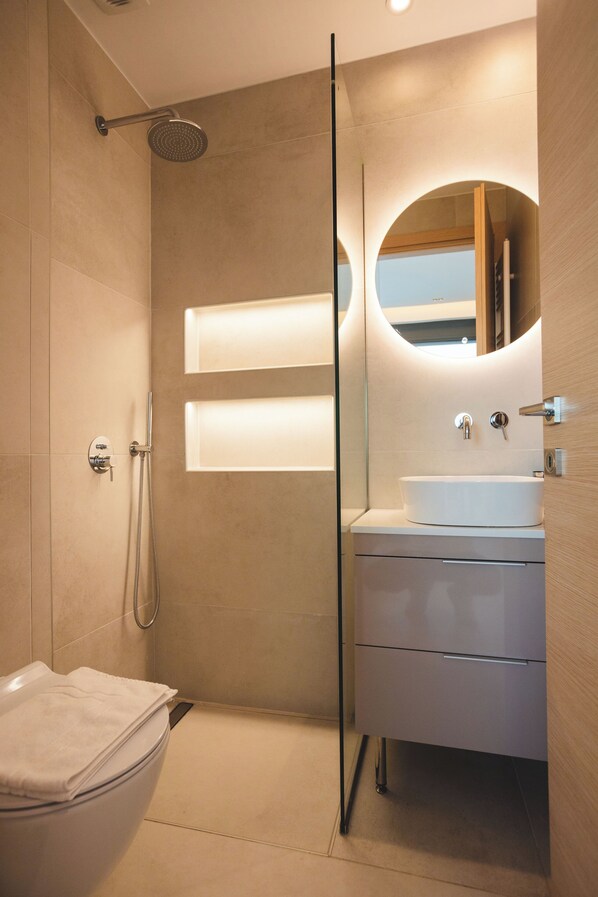 A modern bathroom with a glass shower enclosure, a white sink, and a mirror. - Panoramic Villa Tolo (Tolo)