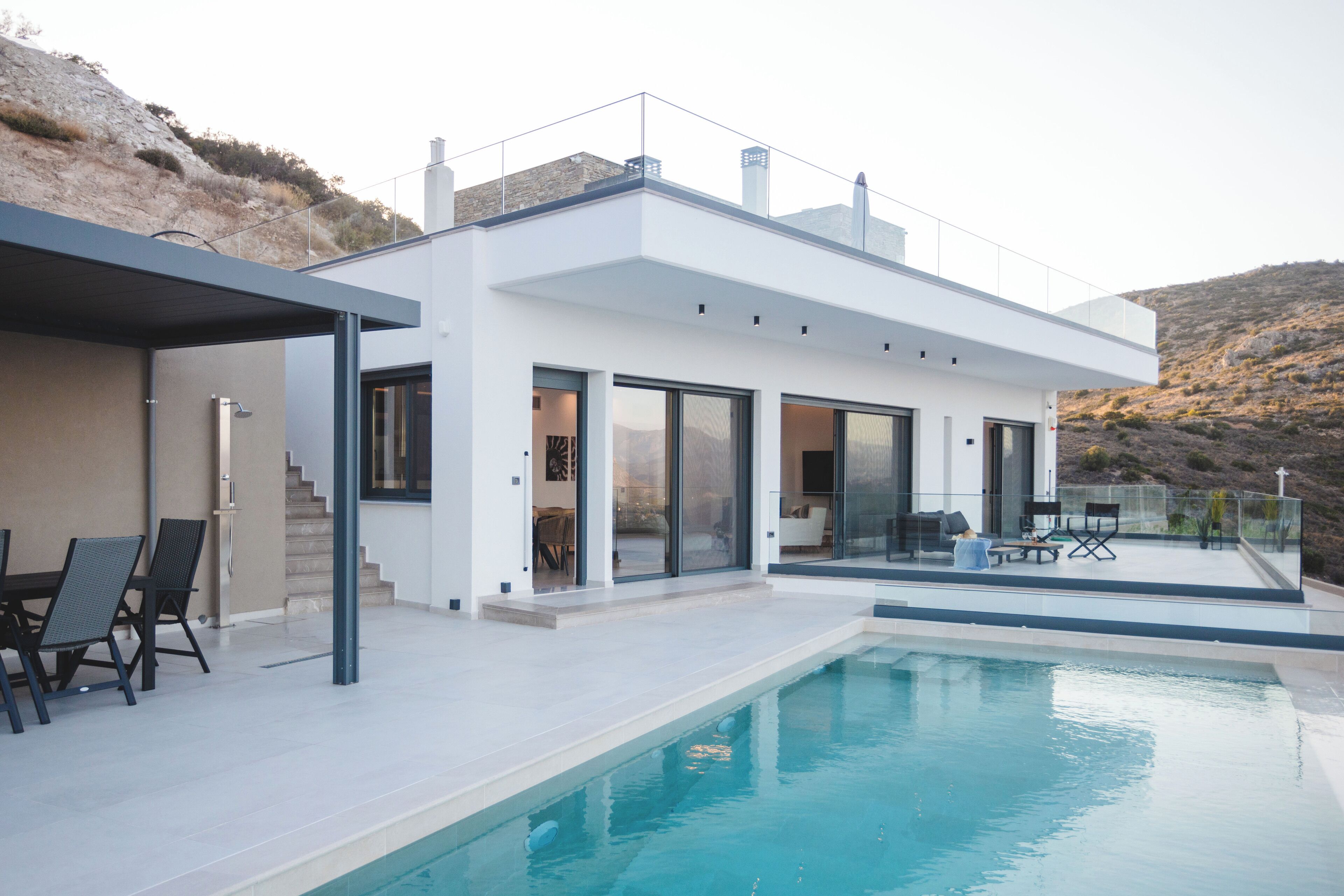 A modern house with a swimming pool, large windows, and a covered patio area.