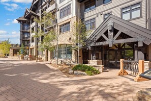 A multi-story building with a stone facade, a covered entrance, and a number '110' sign.