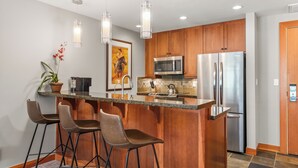 Una cocina moderna con armarios de madera, electrodomésticos de acero inoxidable y una barra con taburetes.