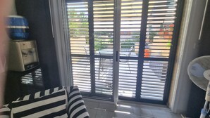 Een kamer met een schuifglasdeur naar een buitenruimte, een kleine tafel met een waterdispenser en een staande ventilator.