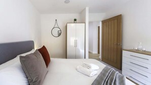 A modern bedroom with a bed, a wardrobe, and a mirror.