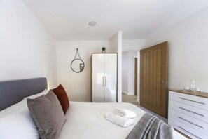 Ein modernes Schlafzimmer mit einem Bett, einem Kleiderschrank und einem Spiegel.